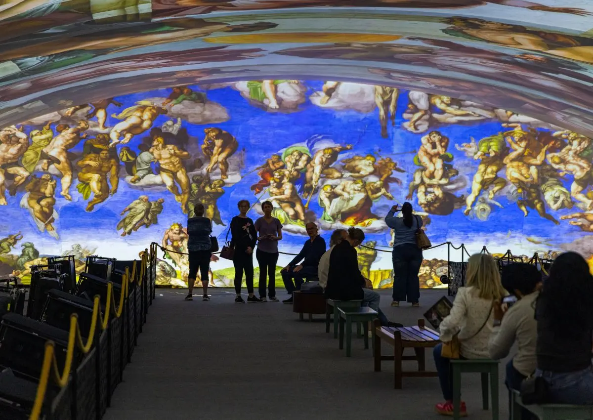 Visitantes observando la proyección del Juicio Final en la exhibición Capilla Sixtina